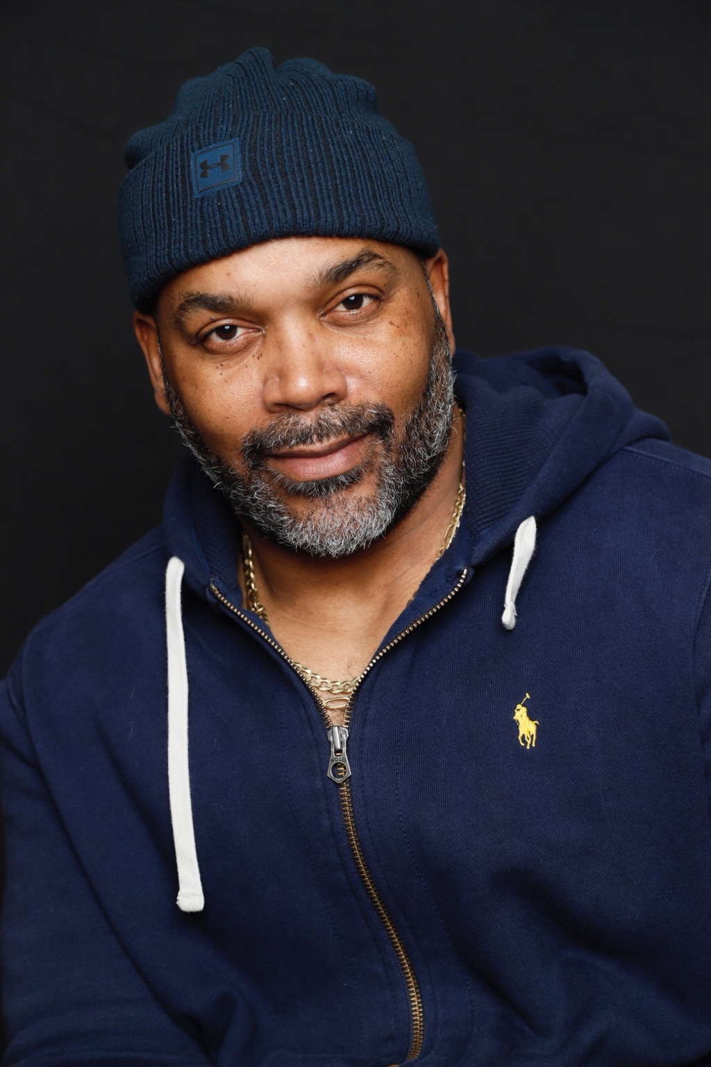 Lucius Alston smiling in a navy hoodie and knit cap